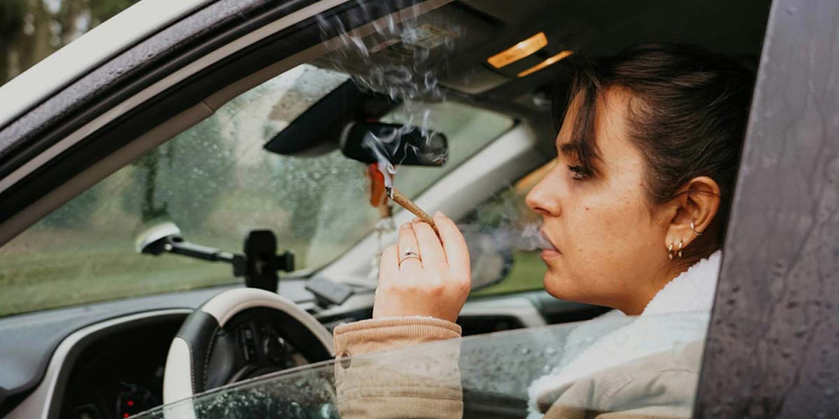 Frau raucht Joint bei offenem Fenster Cannabis am Steuer