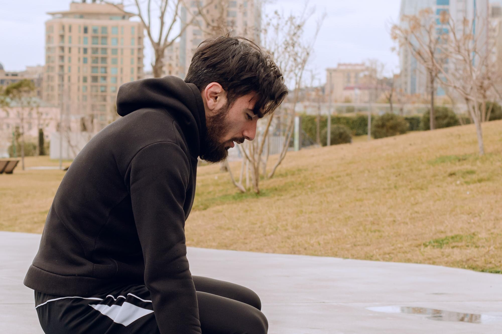 Cannabis Nebenwirkungen – Mann in Trainingskleidung ruht sich im Park aus. Ihm ist schwindelig