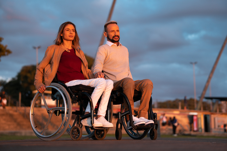 Cannabis bei MS - Ein junges Paar im Rollstuhl blickt in die Ferne. Cannabis könnte helfen .