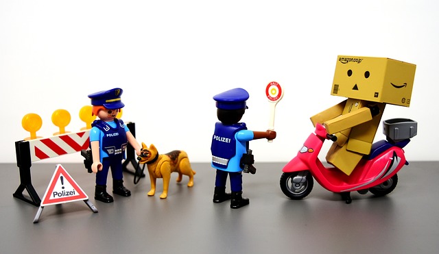 Playmobil-Figuren mit zwei Polizisten und einem Hund bei Verkehrskontrolle stoppen einen Rollerfahrer mit amazon-Karton über dem Kopf